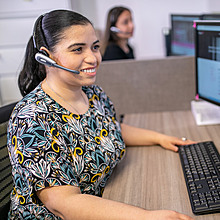 Photo of a young woman with a headset at a computer
